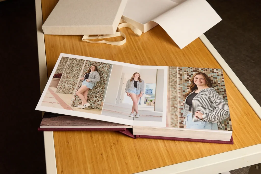 An open album of a fine art senior portrait album on a coffee table, highlighting the tactile and lasting nature of printed photography.